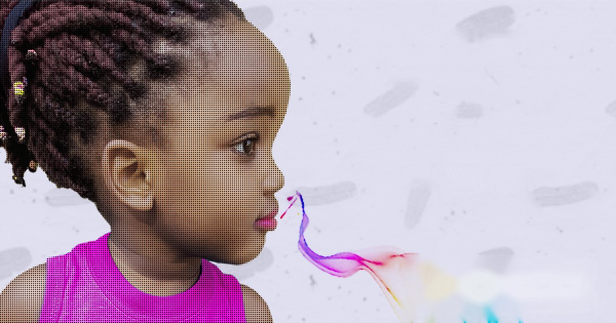 A young girl blowing a ribbon of coloured smoke
